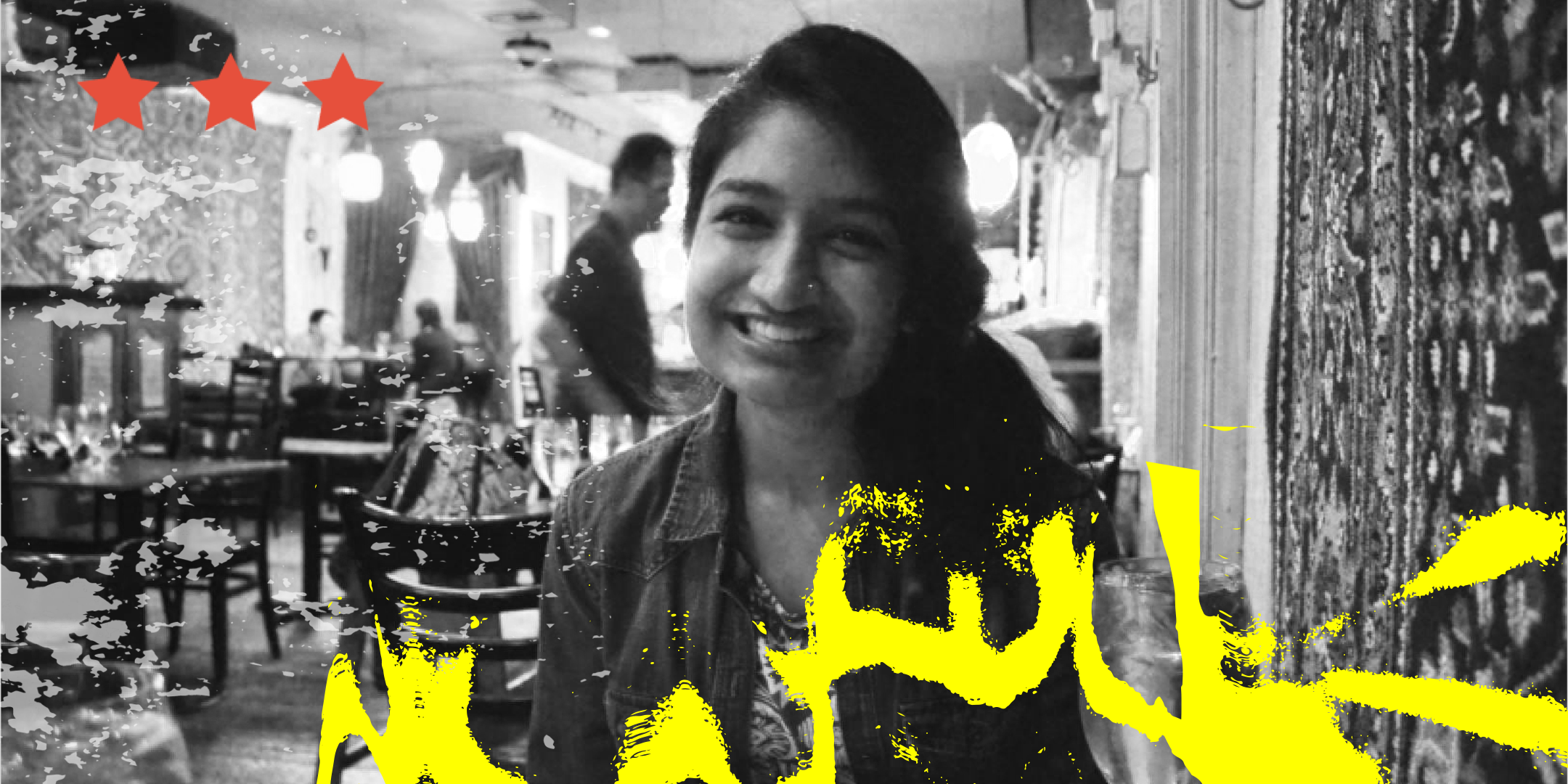 [Kiran Wattamwar] A young, temporarily-abled South Asian American woman smiling warmly at a restaurant table.