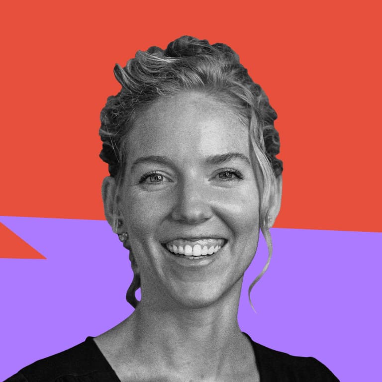 A young white woman with blonde hair with great posture :) and a black jumpsuit laughing towards the camera.