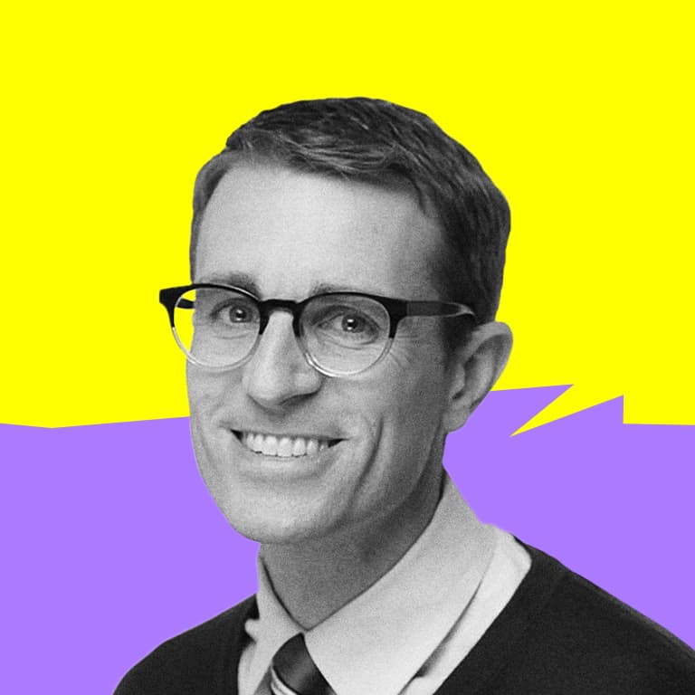 A white man with brown hair and glasses with a blue sweater vest and red tie.