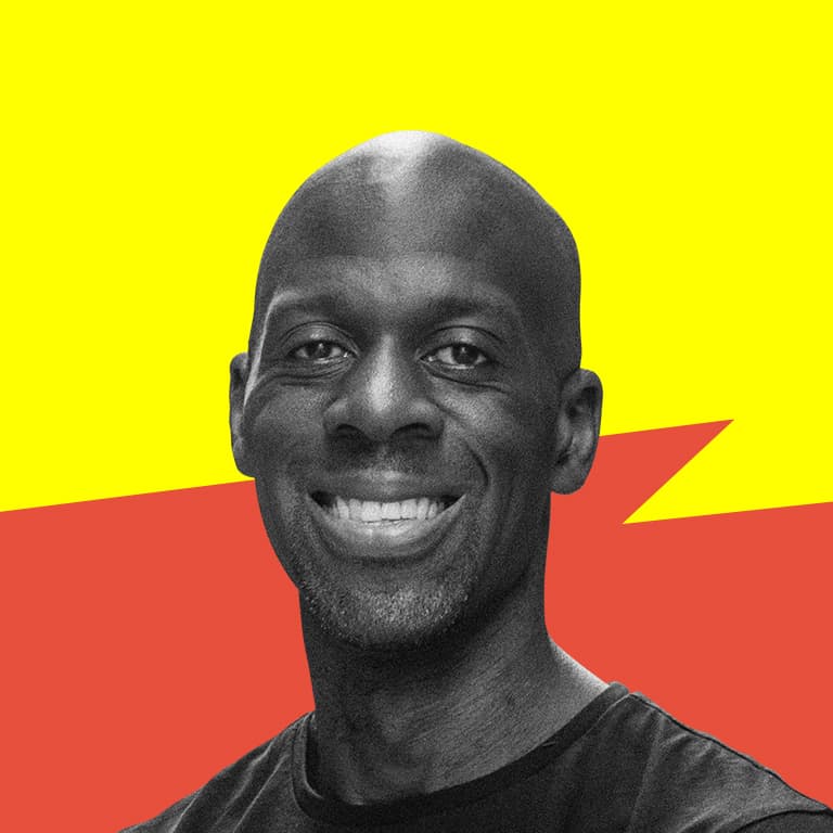 A Black man with a shaved head who is smiling.